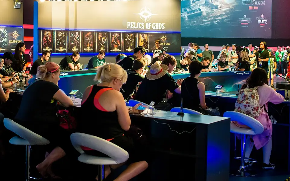 Players seated at a long table playing games on their phones